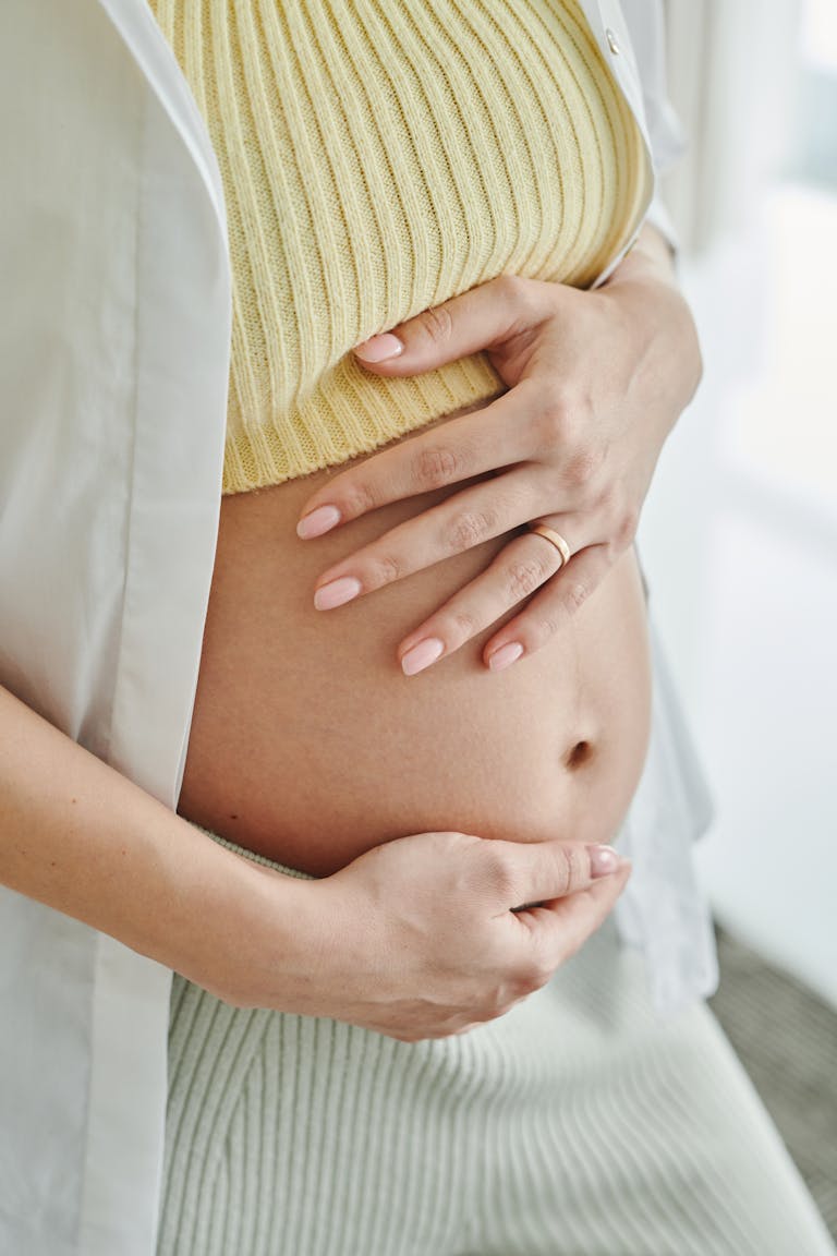 A close-up shot of a pregnant woman's hands gently resting on her belly, symbolizing motherhood.
